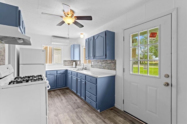 kitchen featuring white appliances, blue cabinetry, a sink, light countertops, and light wood-style floors