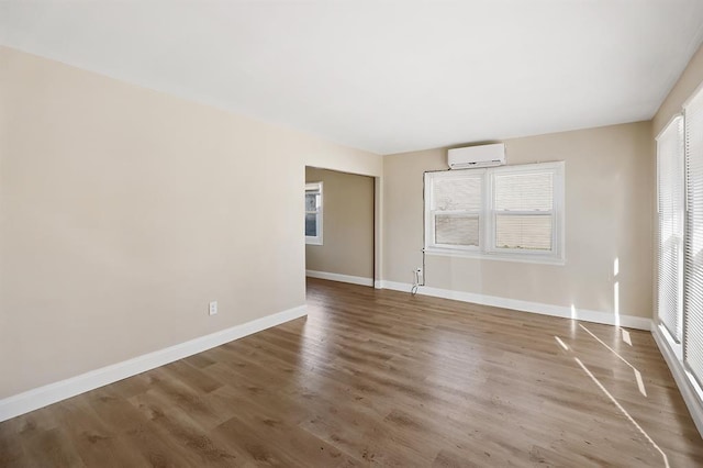 11893 Bridgevale Ave, Saint Louis, MO 63138 - unfurnished living room featuring a wall mounted AC, healthy amount of natural light, wood finished floors, and baseboards