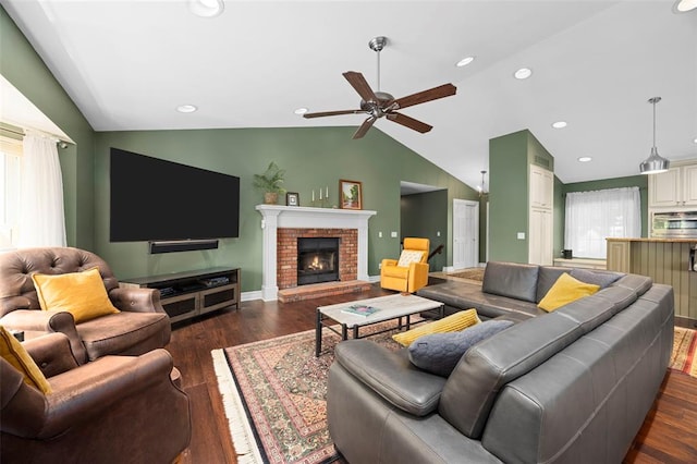 living area with lofted ceiling, dark wood-style floors, ceiling fan, a fireplace, and baseboards