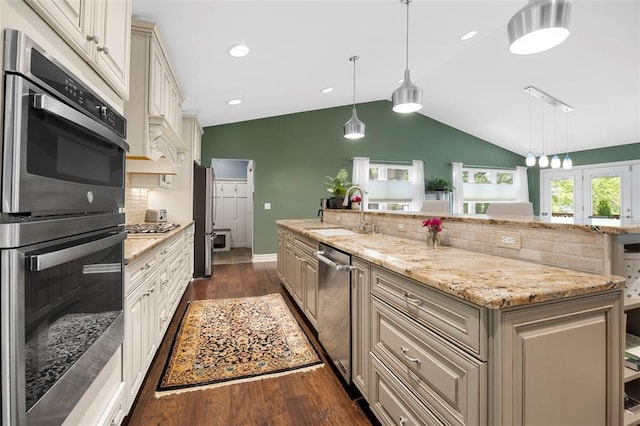 kitchen with a sink, dark wood finished floors, stainless steel appliances, lofted ceiling, and tasteful backsplash