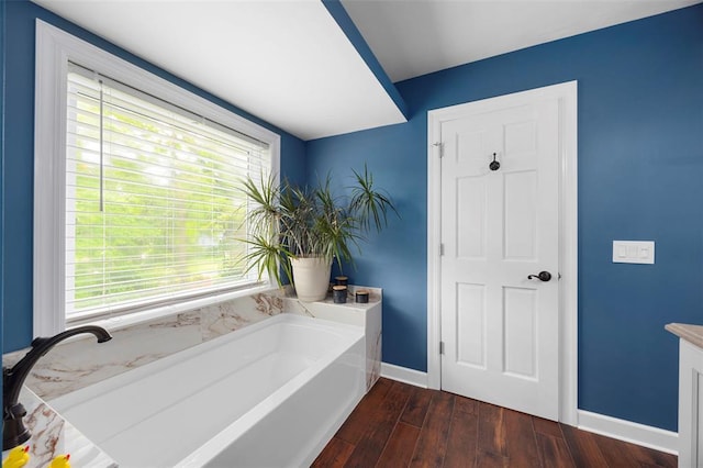 bathroom with baseboards, a garden tub, healthy amount of natural light, and wood finished floors