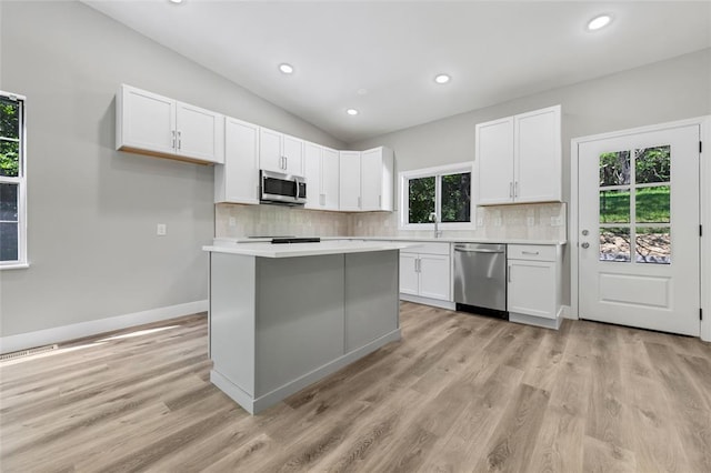 kitchen featuring appliances with stainless steel finishes, backsplash, white cabinets, light countertops, and vaulted ceiling