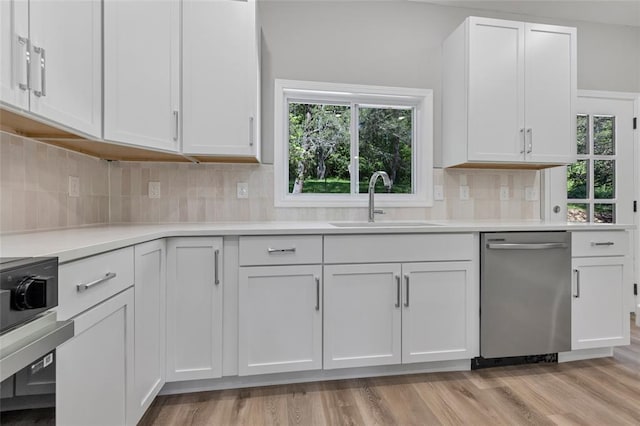 kitchen with stainless steel dishwasher, a sink, white cabinetry, and light countertops