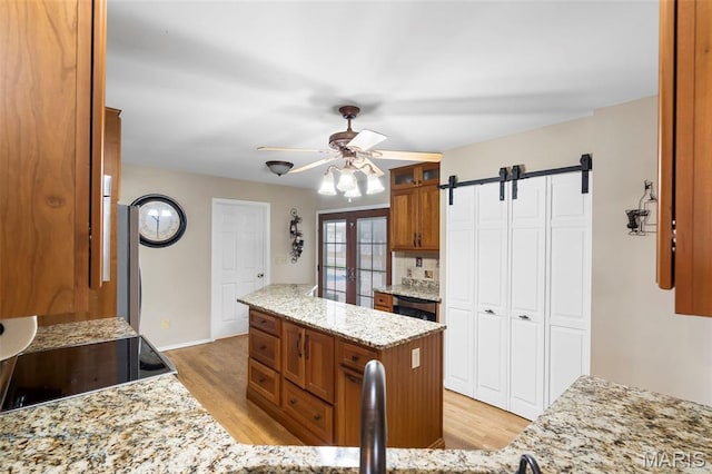 8 Baron Ridge Ct, Ofallon, MO 63366 - kitchen featuring brown cabinets, light wood-style floors, a ceiling fan, and a barn door
