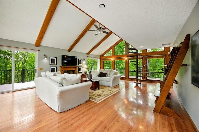 living room featuring ceiling fan, high vaulted ceiling, wood-type flooring, stairway, and beamed ceiling