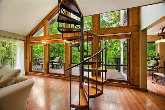 doorway to outside featuring stairs, hardwood / wood-style floors, high vaulted ceiling, and ceiling fan