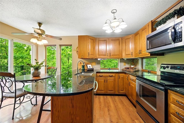 kitchen featuring stainless steel appliances, a sink, a peninsula, plenty of natural light, and a textured ceiling