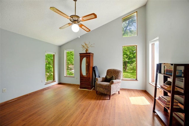 sitting room with high vaulted ceiling, light wood-style floors, ceiling fan, and baseboards