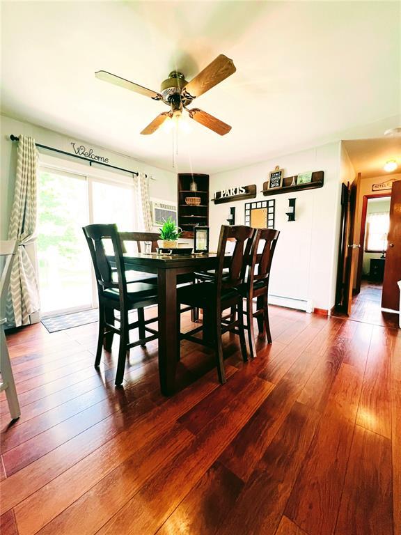 dining room featuring dark wood-type flooring, a ceiling fan, and a baseboard heating unit