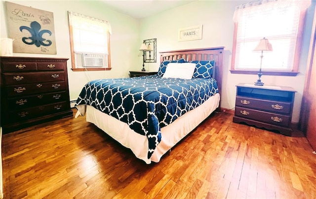 bedroom featuring hardwood / wood-style floors, cooling unit, and baseboard heating