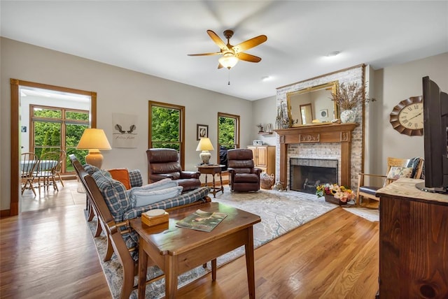 214 Townview Ct, Wentzville, MO 63385 - living area with healthy amount of natural light, a ceiling fan, a brick fireplace, and light wood finished floors