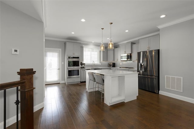 8000 Central Park Dr, Richmond Heights, MO 63117 - kitchen featuring stainless steel appliances, gray cabinetry, ornamental molding, a breakfast bar, and light countertops