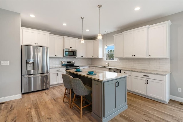 207 Still Creek Dr, Lake St Louis, MO 63367 - kitchen with stainless steel appliances, white cabinetry, a center island, light wood finished floors, and tasteful backsplash
