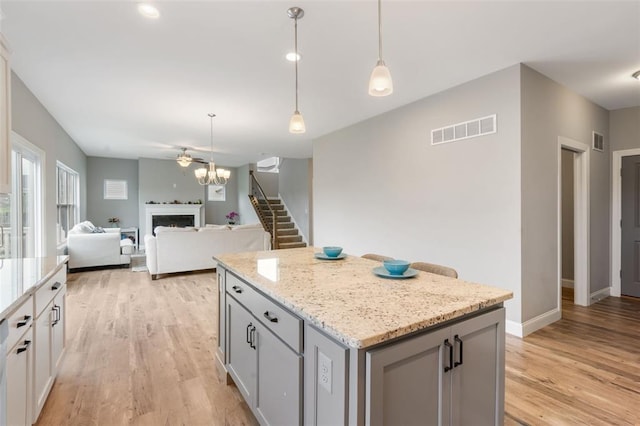 207 Still Creek Dr, Lake St Louis, MO 63367 - kitchen with light wood finished floors, a fireplace, a center island, baseboards, and gray cabinets
