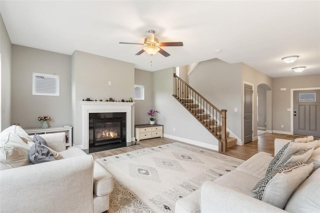 207 Still Creek Dr, Lake St Louis, MO 63367 - living room with light wood-style floors, stairway, ceiling fan, a fireplace with flush hearth, and arched walkways