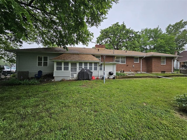 back of property with a lawn, brick siding, and a chimney