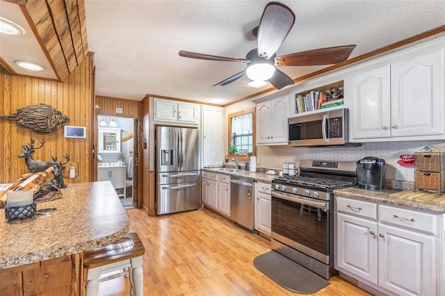 kitchen with appliances with stainless steel finishes, ceiling fan, a textured ceiling, white cabinets, and light wood finished floors