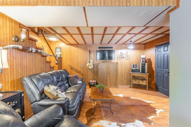living room featuring wood walls, stairs, and wood finished floors