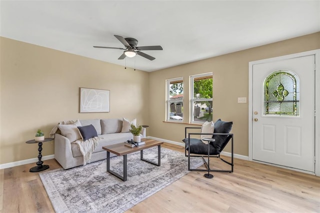living room featuring a ceiling fan, baseboards, and light wood-style floors