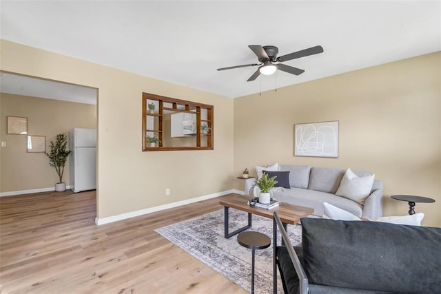 living area with light wood-style flooring, baseboards, and a ceiling fan