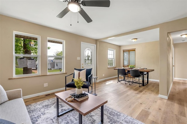 living room with light wood-type flooring, baseboards, and ceiling fan