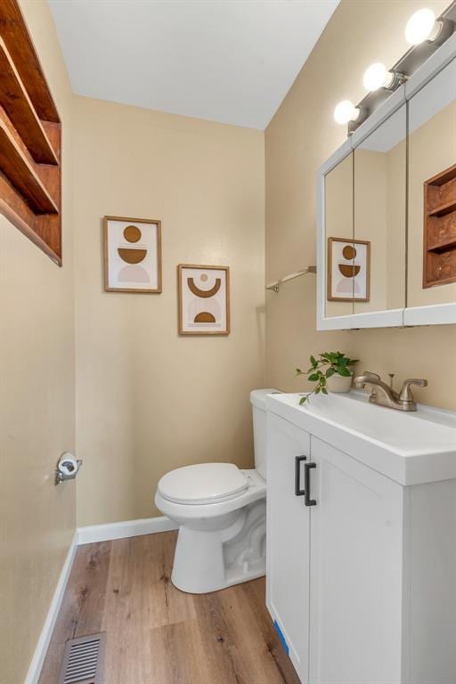 bathroom with toilet, wood finished floors, vanity, and baseboards