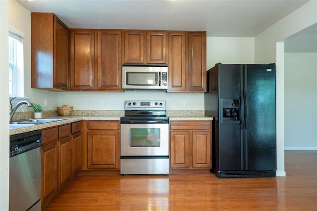1131 Welsh Dr, Lake St Louis, MO 63367 - kitchen featuring stainless steel appliances, brown cabinetry, a sink, light countertops, and light wood-style floors