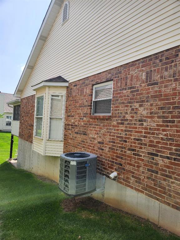 view of side of home featuring central air condition unit, brick siding, and a lawn