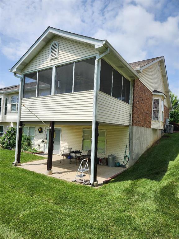 rear view of property featuring a patio area, a sunroom, a yard, and central AC unit