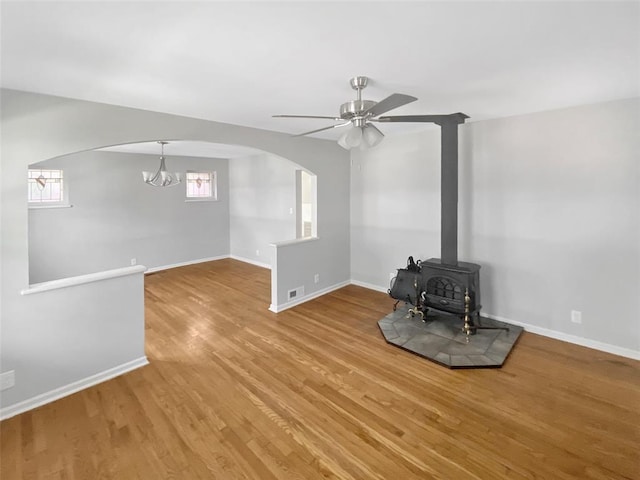 6504 Hoffman Ave, Saint Louis, MO 63139 - unfurnished living room with arched walkways, wood finished floors, a ceiling fan, a wood stove, and baseboards