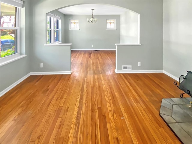6504 Hoffman Ave, Saint Louis, MO 63139 - spare room featuring a chandelier, arched walkways, wood finished floors, and baseboards