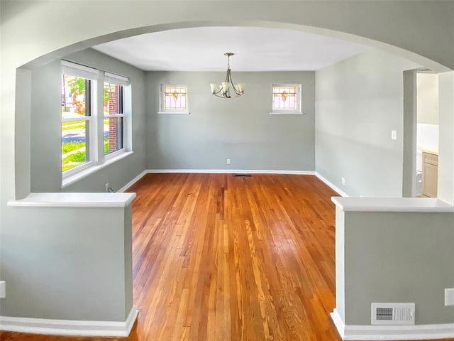 6504 Hoffman Ave, Saint Louis, MO 63139 - spare room featuring hardwood / wood-style floors, a chandelier, and arched walkways