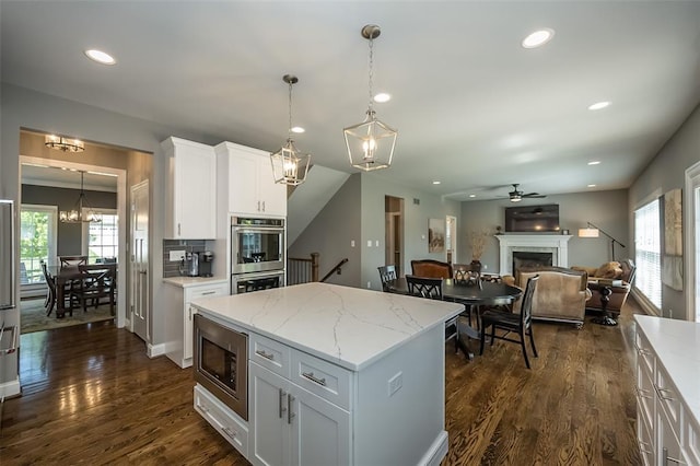 1026 Barry Ct, Kirkwood, MO 63122 - kitchen with a fireplace, appliances with stainless steel finishes, a chandelier, ceiling fan, and dark wood finished floors