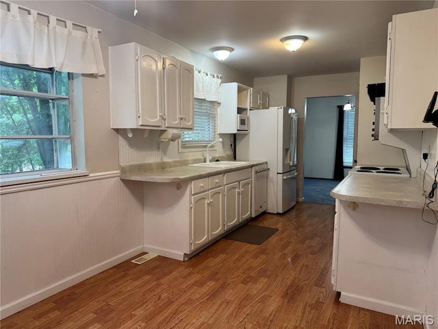 5810 White Pine Dr, Saint Louis, MO 63129 - kitchen with dishwashing machine, dark wood-style flooring, light countertops, freestanding refrigerator, and white cabinets