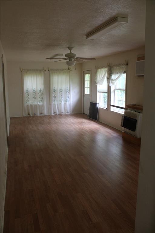 unfurnished living room featuring a textured ceiling, wood finished floors, ceiling fan, and an AC wall unit