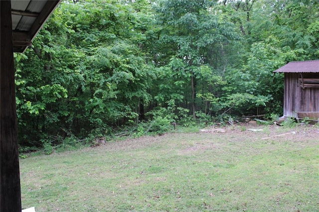 view of green lawn featuring a wooded view