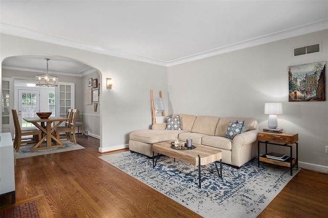 living room with arched walkways, wood finished floors, baseboards, and crown molding