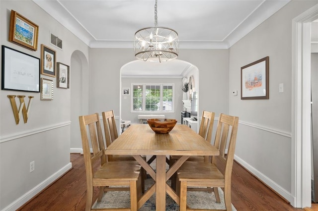 dining area with arched walkways, wood finished floors, a chandelier, crown molding, and baseboards
