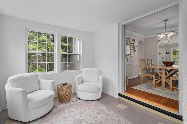 sitting room featuring plenty of natural light, tile patterned flooring, a chandelier, arched walkways, and ornamental molding