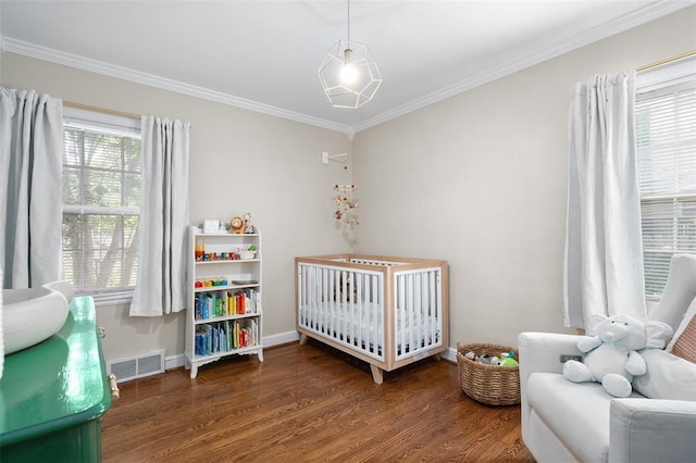bedroom featuring wood finished floors, ornamental molding, a nursery area, and baseboards