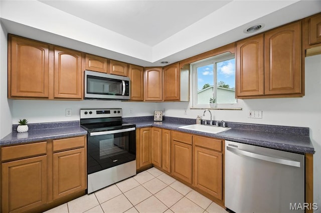 2649 Georgia Dr, Arnold, MO 63010 - kitchen featuring appliances with stainless steel finishes, light tile patterned floors, dark countertops, and brown cabinetry