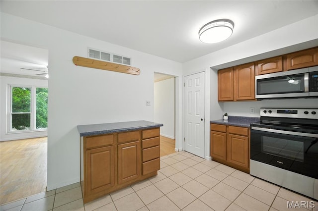 2649 Georgia Dr, Arnold, MO 63010 - kitchen featuring stainless steel appliances, dark countertops, light tile patterned flooring, and brown cabinetry