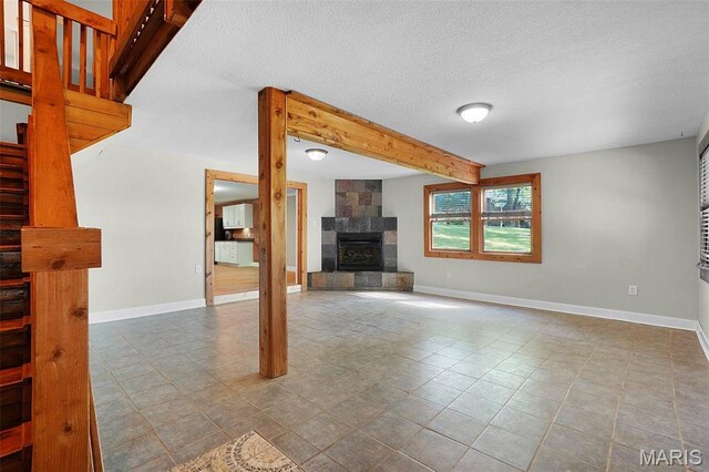 14938 Pike 139, Bowling Green, MO 63334 - unfurnished living room featuring a tiled fireplace, stairway, baseboards, a textured ceiling, and beamed ceiling