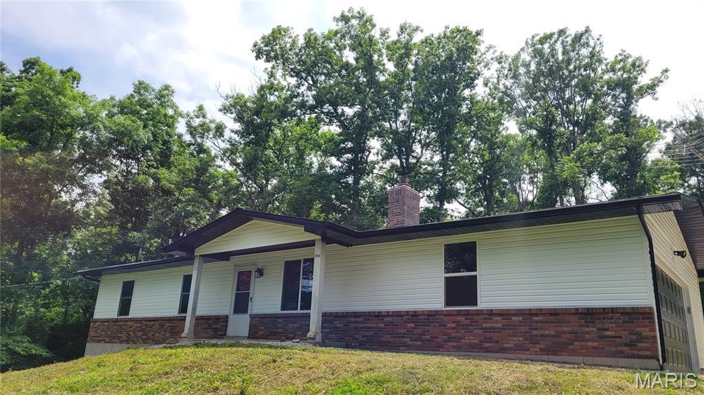 8708 Canyon Ln, Dittmer, MO 63023 - ranch-style home featuring brick siding, a front lawn, a chimney, and covered porch