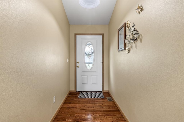 doorway with dark wood-style flooring and baseboards