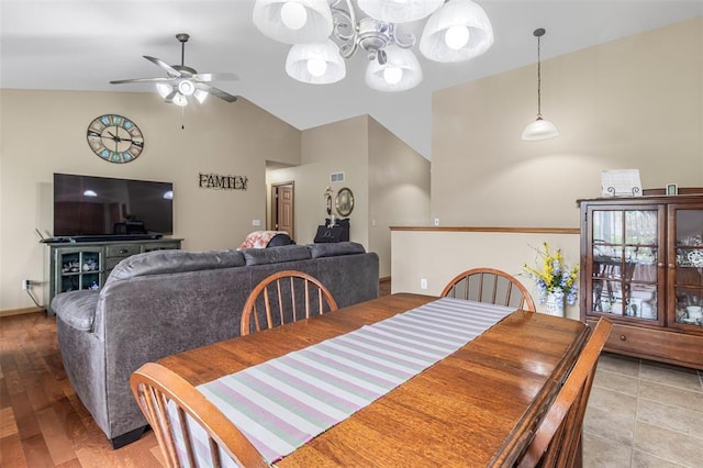 dining area featuring a ceiling fan, a chandelier, high vaulted ceiling, and wood finished floors