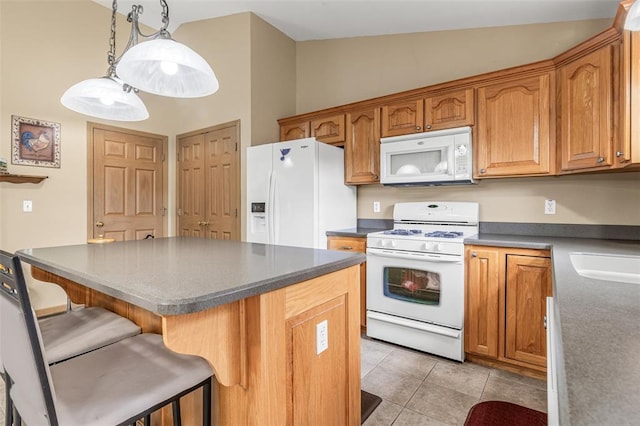 kitchen with white appliances, a kitchen bar, light tile patterned floors, brown cabinets, and pendant lighting