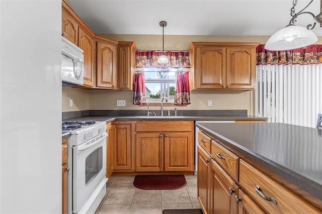 kitchen with a sink, white appliances, dark countertops, and brown cabinets