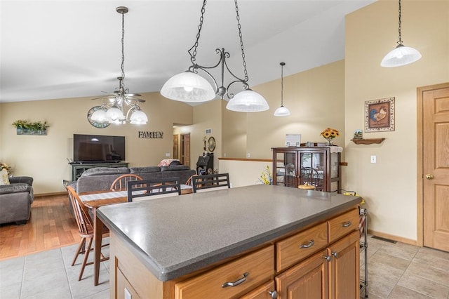 kitchen featuring a breakfast bar area, open floor plan, a ceiling fan, dark countertops, and high vaulted ceiling