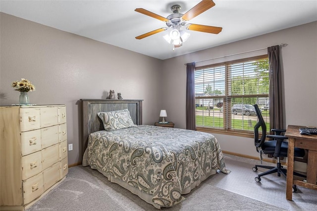 bedroom with light carpet, baseboards, ceiling fan, and an office area